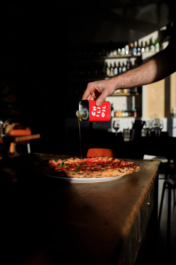 OLEA PIA Chili Oil 250 ml wird über Pizza gegossen